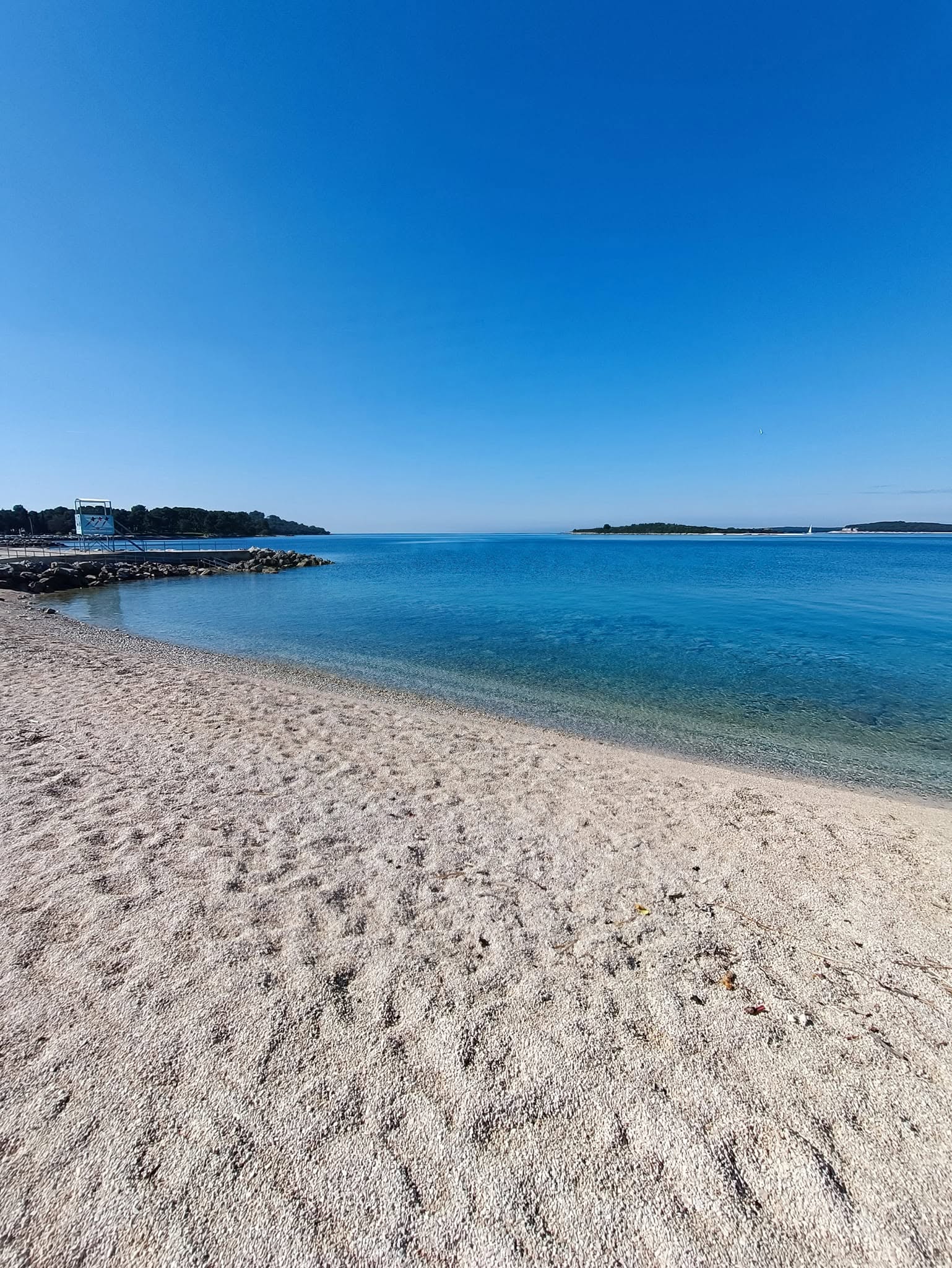 Ampia spiaggia di ciottoli e mare calmo a Pula